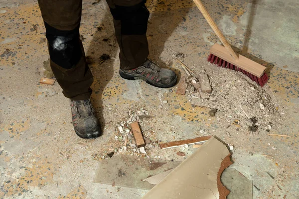 İnşaat atıklarıyla kaplı beton zeminde duran iş botları. Yenileme, işyeri güvenliği, sanayi ortamı, el işçiliği ve inşaat sonrası bakım kavramı