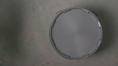 Elle sıvama araçlarını bir kova kapağına yerleştirirken tepeden aşağı görünüm, yenileme veya inşaat çalışmalarına temiz bir asgari ayarda hazırlanmak