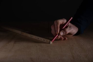 Ahşap zemindeki katlama cetvelini kullanarak el işaretleme ölçüsünü kalemle kapat. Ev yenileme, marangozluk, doğru ölçüm ve DIY iç onarım kavramı.