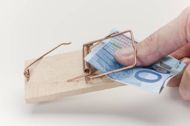 Beyaz arka planda 20 Euro 'luk banknota uzanırken başparmak bir fare kapanına takıldı..