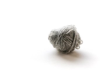 Beyaz arkaplanda küçük gri bir iplik yumağının yüzeysel açısı.