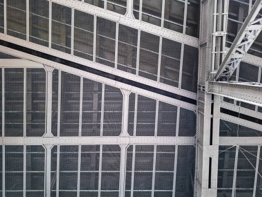 Izgaraları olan perçinlenmiş çelik bir yapının tam ekran görüntüsü.