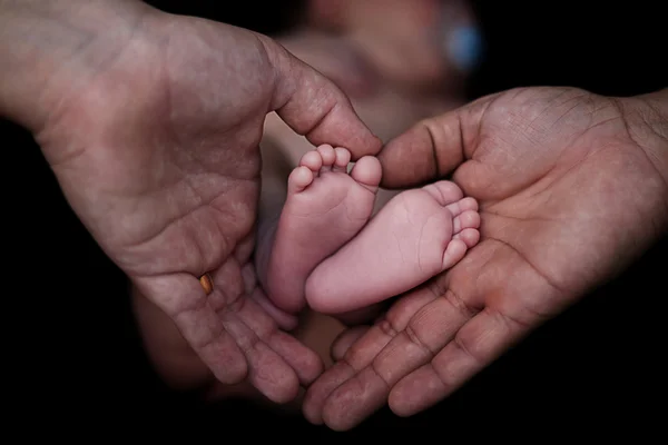 Father\'s hands forming a heart at the feet of son