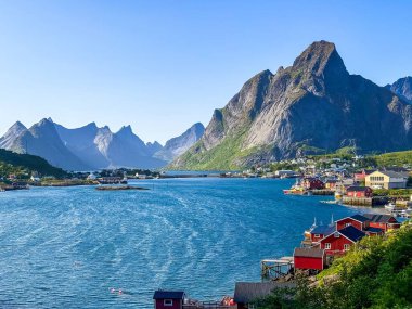 Kırmızı kulübeleri, durgun mavi suları, yüksek granit tepeleri ve demirli tekneleri, ağları ve balıkçılık endüstrisini öneren ahşap iskeleleri olan güneşli fiyort köyü.