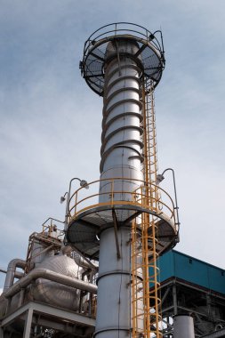 Sağlam metal iskeleti ve uzun silindirik egzoz yığınına sahip karmaşık endüstriyel altyapının ayrıntılı görüntüsü. Modern çağda mühendislik mahareti ve teknolojik gelişim.