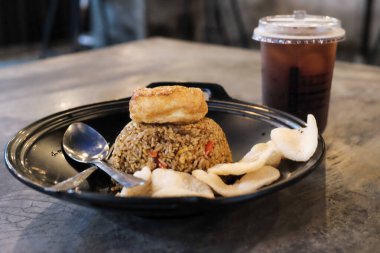 Geleneksel krakerler ve ferahlatıcı bir buzlu içecek ile servis edilen nefis bir tabak Nasi Goreng, restoran menüleri, yemek blogları veya mutfak temalı projeler için mükemmel. Endonezya yemeğinin tadını çıkar.