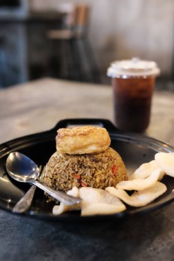 Endonezya 'dan Nasi Goreng' in büyüleyici bir görüntüsü, Krupuk krakerleri ve taze buzlu çayın yanında güzel bir şekilde sunulmuş, Güneydoğu Asya mutfağının özünü yansıtıyor.