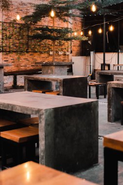 Beton masaları ve alacakaranlık havasında parlayan sicim ışıkları olan rahat bir kafeterya..