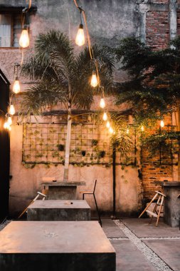 Konforlu açık hava yemek alanı. Tel ışıklarla aydınlatılmış. Alacakaranlıkta sakin bir ortam yaratıyor.