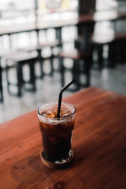 Tazeleyici buzlu kahve ahşap bir masada oturur, sıcak bir günde serinliği ve rahatlığı davet eder..