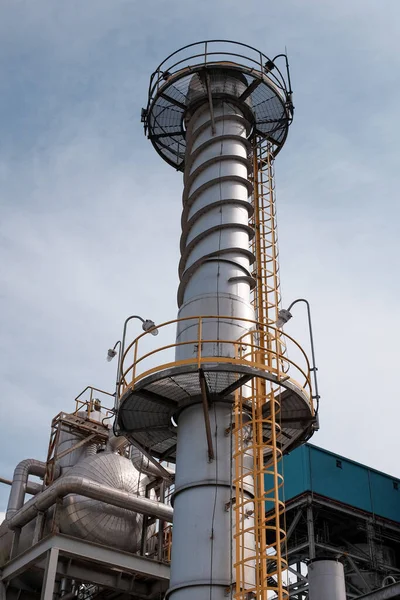 Sağlam metal iskeleti ve uzun silindirik egzoz yığınına sahip karmaşık endüstriyel altyapının ayrıntılı görüntüsü. Modern çağda mühendislik mahareti ve teknolojik gelişim.