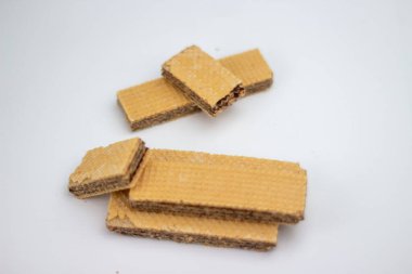 Çikolatayla dolu yığınla wafer kurabiyesi parlak, pürüzsüz, temiz beyaz bir yüzeye oturur.