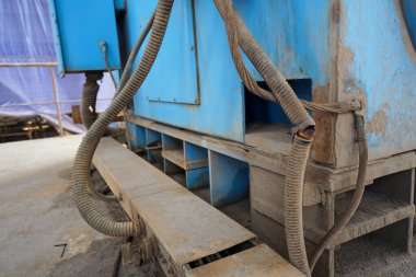 Görüntü, yıpranmış mavi kabloyla birlikte endüstriyel ekipmanlara sahip. Kurulum bir fabrika, inşaat alanı veya atölye gibi görünüyor.
