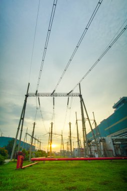 Bu görüntü yüksek voltajlı iletim kuleleri olan bir elektrik santralini gösteriyor. Elektrik santrali ve elektrik altyapısı, evler için elektrik tedarik ve dağıtımına katkıda bulunmaktadır.