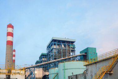 Bu fotoğraf bir elektrik santralinin endüstriyel yapısını yakalıyor, karmaşık altyapısını ve yükselen bacasını gösteriyor. Sahne, çelik yapıların karmaşık ağını vurguluyor,