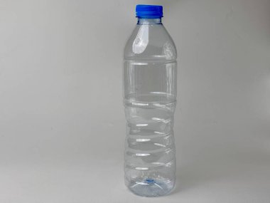 Tarafsız bir zemin üzerinde mavi kapaklı izole edilmiş boş plastik su şişesi, geri dönüşüm kavramlarını ve çevresel farkındalığı görselleştirmek için ideal, içecek modelleri ve ilgili tasarımlar
