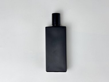 Pürüzsüz, minimalist dikdörtgen siyah bir şişe parlak beyaz bir arka planda izole bir şekilde duruyor. Şişe, parfüm, temel yağlar veya kozmetik ürünleri için modern ve zarif bir tasarım sergiliyor..