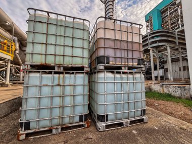 Endüstriyel tesiste yığılmış orta büyüklükteki konteynırlar depolama ve lojistik yönetimini gösteriyor