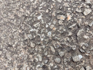Detaylı yakın plan çekimleri, küçük taşlar ve çakıl taşları desenli eskimiş beton yüzeyi gösteriyor.