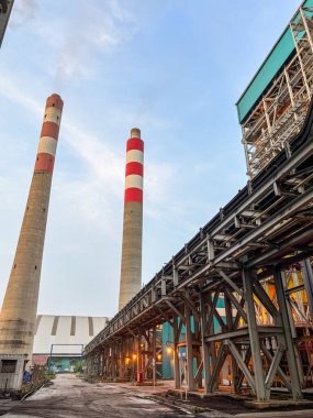 Gündüz vakti gökyüzüne karşı bacalar ve metalik yapıya sahip sanayi manzarası