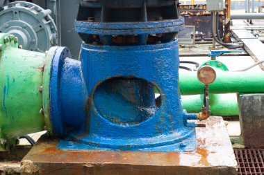 Yakın plan çekimde mavi ve yeşil bileşenleriyle ayırt edilen endüstriyel su pompası sistemi sergileniyor. Pas ve aşınma ile işaretlenmiş yıpranmış görünüş, makinelerin yaşını ve