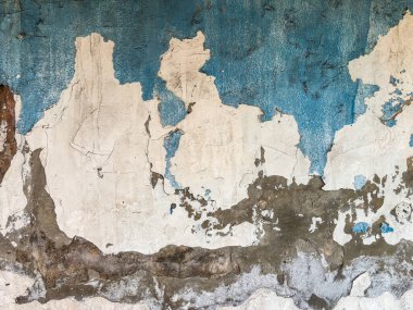 Sıkıntılı mavi ve beyaz boyalı duvar soyut bir perde arkası yaratıyor, rustik bir ortam.