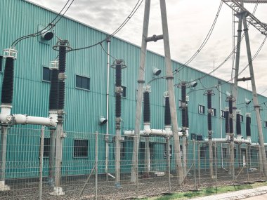 Trafo ekipmanları, bulutlu hava koşullarında güvenlik çiti arkasında enerji şebekesine güç veriyor..