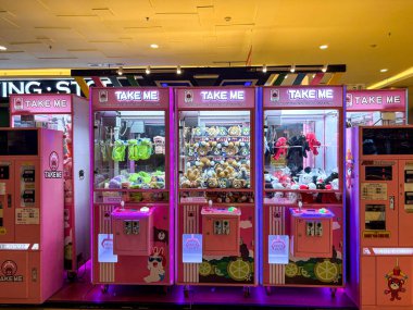 Doldurulmuş oyuncaklarla dolu büyüleyici pembe pençe makineleri oyun salonunu bekliyor.