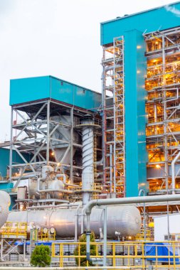 Bu görüntü, modern imalata güç katan karmaşık boru, yapı ve mimari dehayı gösteren genişleyen bir sanayi kompleksini yakalıyor. Mavi renkler.