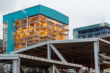 Bu resim, sağlam altyapısını ve karmaşık metal yapısını vurgulayan bir enerji santralini gösteriyor. Mimari tasarım, mavi aksanıyla, teknolojik gücü ve