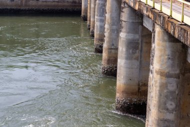 Yıpranmış beton köprü rıhtımlarının manzarası bir nehirde sıkıca duruyor. Altyapı, görünürdeki yıpranma ve yıpranma ile yaşını göstererek yapıya karakter katıyor. Akan su bir dinamik yaratır.