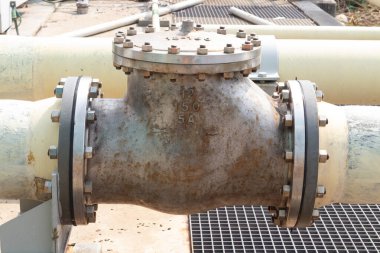 Endüstriyel bir boru hattına yakın plan, flanşlar, fındıklar ve cıvatalar güvenli ve sızdırmaz bir bağlantı sağlıyor. Metalin yıpranmış görünüşüne bakılırsa...