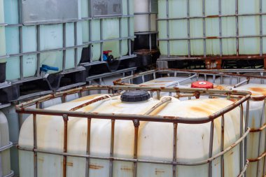 Endüstriyel ortamda istiflenmiş orta büyüklükteki konteynırlar. Konteynırlar sıvı ve malzeme depolamak ve taşımak için kullanılır, takviye için bir kafes ve