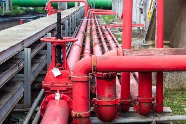 Endüstriyel bir tesisin karmaşıklığını ve önemli altyapısını gösteren kırmızı endüstriyel boru ve vanalardan oluşan bir ağ. Boru hatları sıvı ve gaz taşımacılığının önemini vurguluyor,