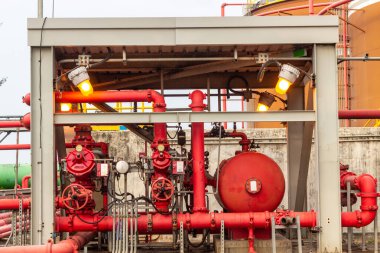 Kırmızı boru valfleri ve destek yapılarından oluşan karmaşık bir endüstriyel boru hattı sisteminin ayrıntılı görüntüsü. Görüntü, sistemin karmaşık mühendisliğini ve yapısını gösteriyor.,
