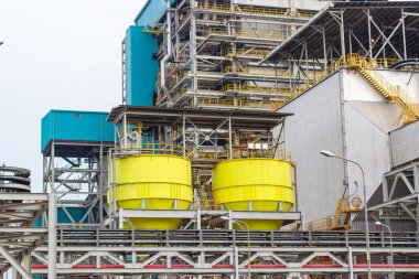 Bu görüntüde, öne çıkan sarı depolama tankları ve karmaşık çelik yapılar içeren büyük bir sanayi kompleksi yer alıyor. Tesis imalat, enerji veya petrokimyasal sektörleri temsil etmektedir..