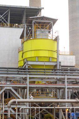 Sarı siloların sergilendiği bir sanayi bölgesinin detaylı bir görüntüsü ve karmaşık bir boru hattı ağı. Görüntü, tesisteki karmaşık altyapıyı ve operasyonların ölçeğini vurguluyor.