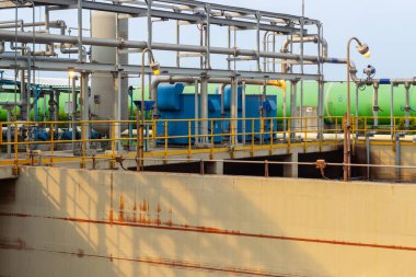 Bu görüntü, arıtma işlemi için gerekli olan boru, tank ve yapıların yer aldığı bir endüstriyel su arıtma tesisini gösteriyor. Tesis mühendislik, teknoloji ve