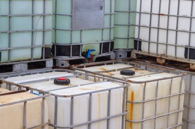 Yakın çekimde, endüstriyel dayanıklılıklarını ve tasarımlarını vurgulayan bir yığın orta büyüklükteki konteynır (IBC) sergilenir. Plastikten yapılmış ve metal kafeslerle güçlendirilmiş bu IBC 'ler...