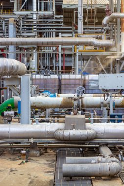 Bu fotoğraf, modern imalatın karmaşıklığını gözler önüne sererek, boruların ve endüstriyel altyapının karmaşık ağını yakalıyor. Metal boru ve valflerden oluşan bir ağ detaylı bir şekilde oluşturur.