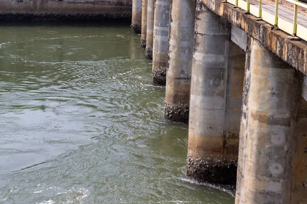 Yıpranmış beton köprü rıhtımlarının manzarası bir nehirde sıkıca duruyor. Altyapı, görünürdeki yıpranma ve yıpranma ile yaşını göstererek yapıya karakter katıyor. Akan su bir dinamik yaratır.