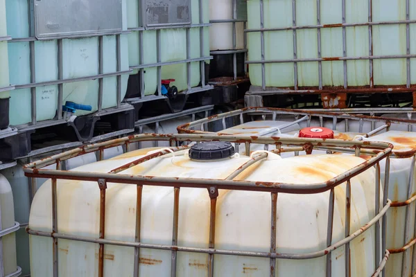 Endüstriyel ortamda istiflenmiş orta büyüklükteki konteynırlar. Konteynırlar sıvı ve malzeme depolamak ve taşımak için kullanılır, takviye için bir kafes ve