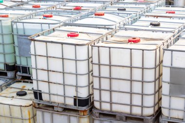 Sıvıların depolanması ve taşınması için Orta büyüklükteki Toplu Konteynırlar (IBC) yığını. Bir dağıtım merkezinde endüstriyel konteynırlar. Üretim ve lojistik işlemleri için sıvı kullanımı.