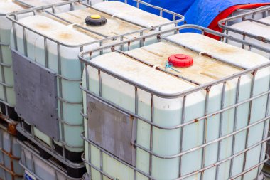 Toplu konteynırlar kimyasal ürün dağıtımı ve işleme için küresel kaynak yönetim ekipmanlarını gösteren çelik çerçeveli bir konteynırda büyük miktarda sıvı gösteriyor..