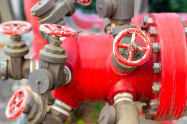 Endüstriyel boru valfleri ve flanşların detaylı düzenlenmesini gösteren yakın plan bir çekim su veya gaz yönetim sisteminde mühendislik karmaşıklığı ve fonksiyonel tasarımı gözler önüne seriyor. Parlak kırmızı