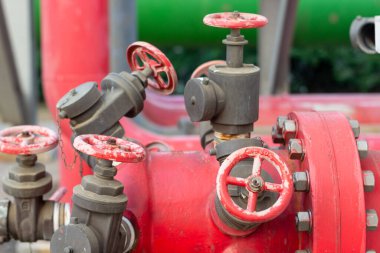 Su basıncını ve çeşitli endüstriyel uygulamalarda sıvı akışını kontrol etmek için kapakçık tekerleklerini birleştiren kırmızı endüstriyel boru hattı sisteminin yakın çekimi..