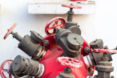 Şehir güvenliğinin temel unsurlarını vurgulayan parlak bir arkaplan üzerine kurulmuş, bir dizi valf ve eşleşme içeren canlı bir kırmızı yangın musluğu manifoldunu yakalayan yakın plan bir resim