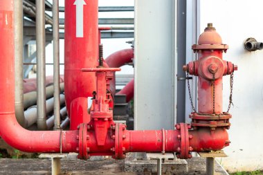 Boruları, vanaları ve dışarıda yangın musluğu olan kırmızı yangın güvenlik sistemi. Bu endüstriyel su taşıma altyapısı acil durum koruması ve bakım için tasarlanmıştır..