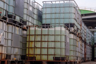 Endüstriyel veya depolama ortamında bulunan orta büyüklükteki konteynırlar (IBC). Bu tanklar toplu sıvıları depolamak ve taşımak için kullanılır ve etkili olması için paletlere yerleştirilir.