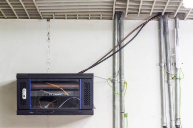 Açık kablolar ve borularla donatılmış ağ sunucu rafı, beyaz bir duvara karşı, pratik ve işlevsel bir çalışma ortamı öneriyor, kapalı,